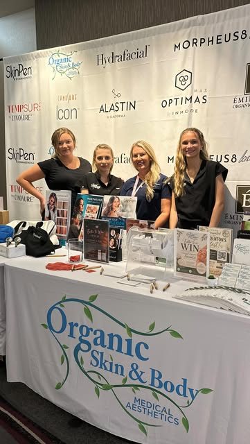 The Organic Skin & Body Medical Aesthetics team at their booth with SkinPen Elite, Hydrafacial and Morpheus8 signage