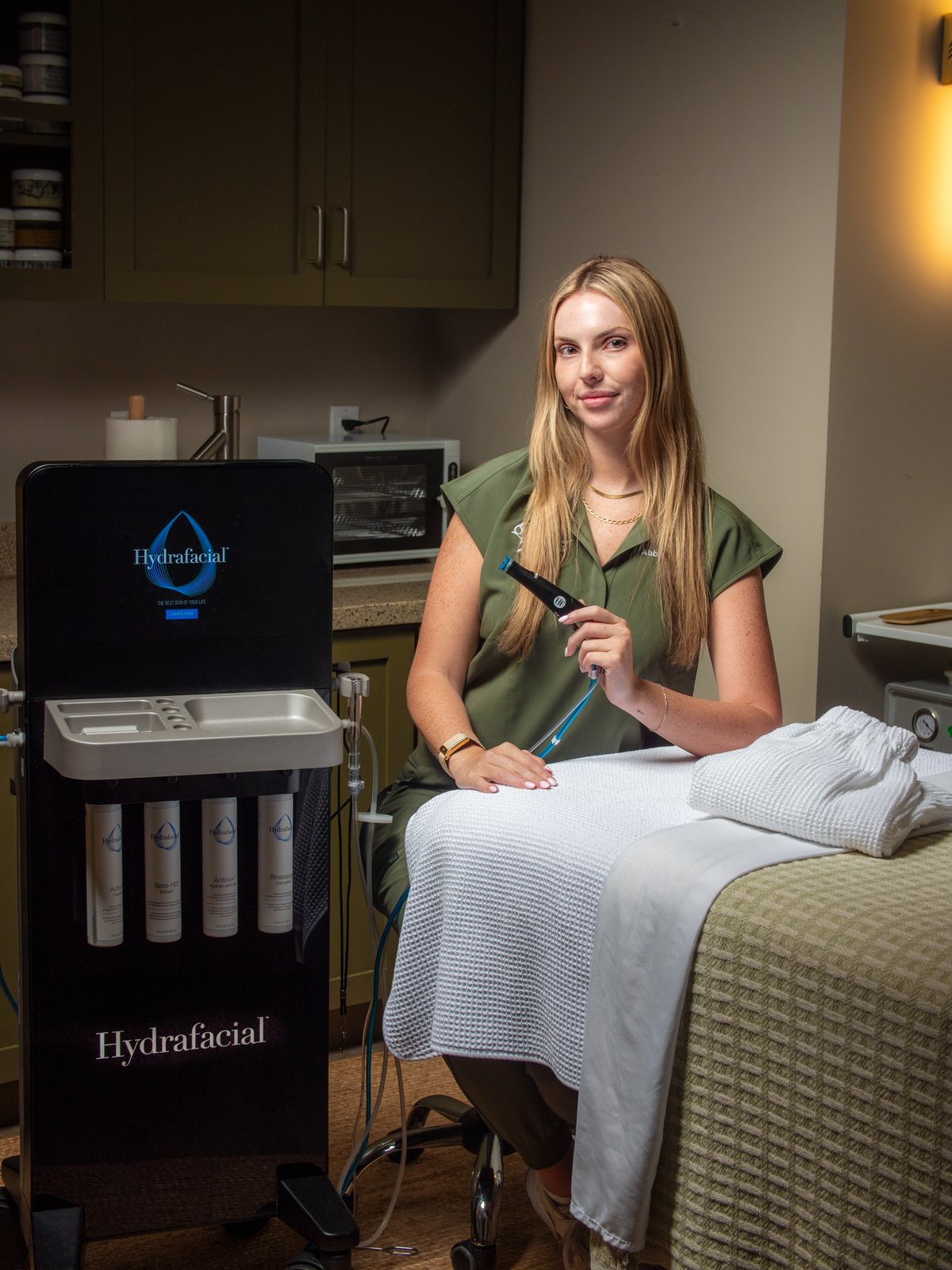 Organic Skin and Body provider seated beside the Hydrafacial system in a Bradenton treatment room, near Lakewood Ranch